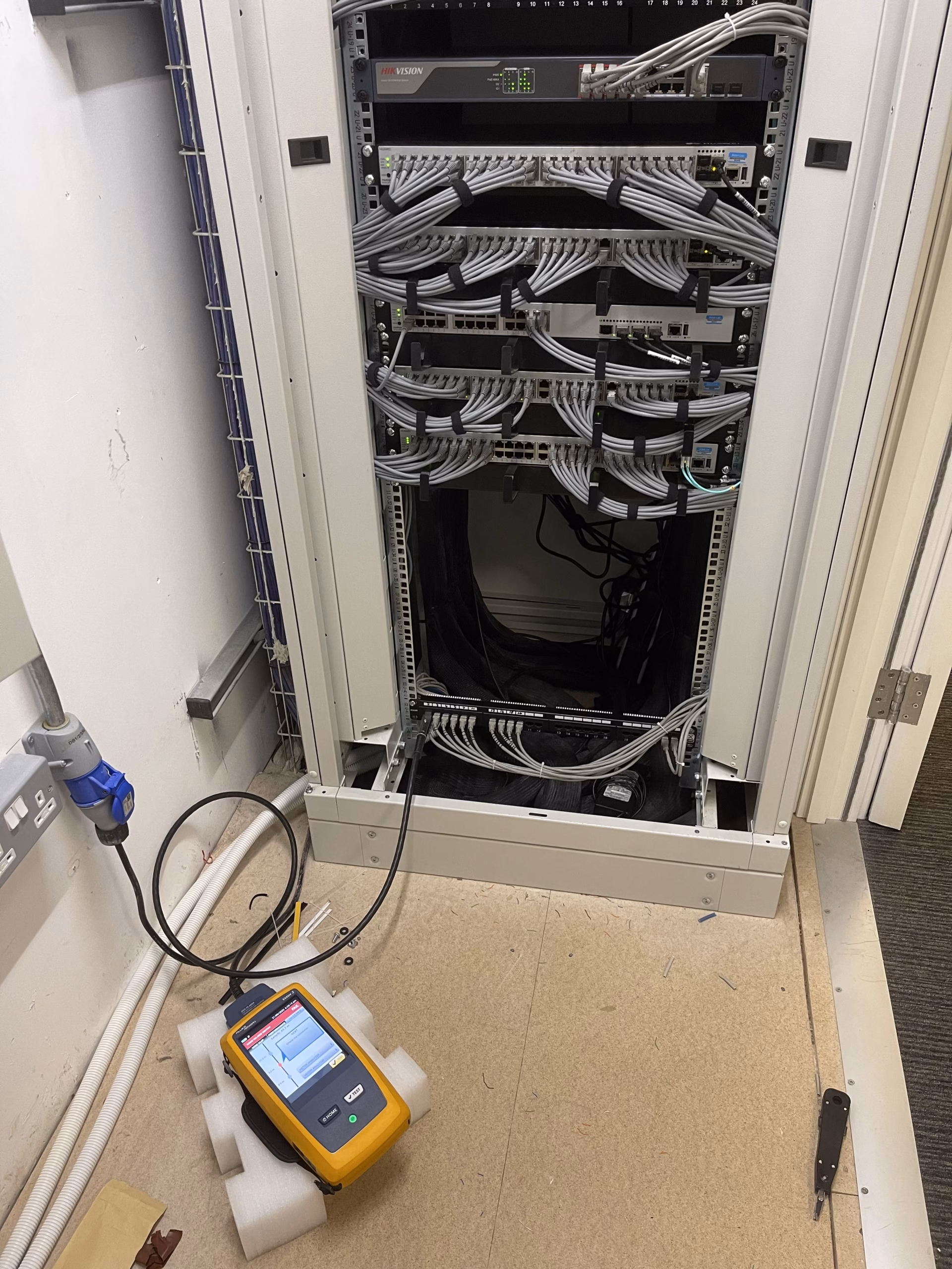 Comms cabinet at Brunswick House — patched and tested with the Fluke DSX